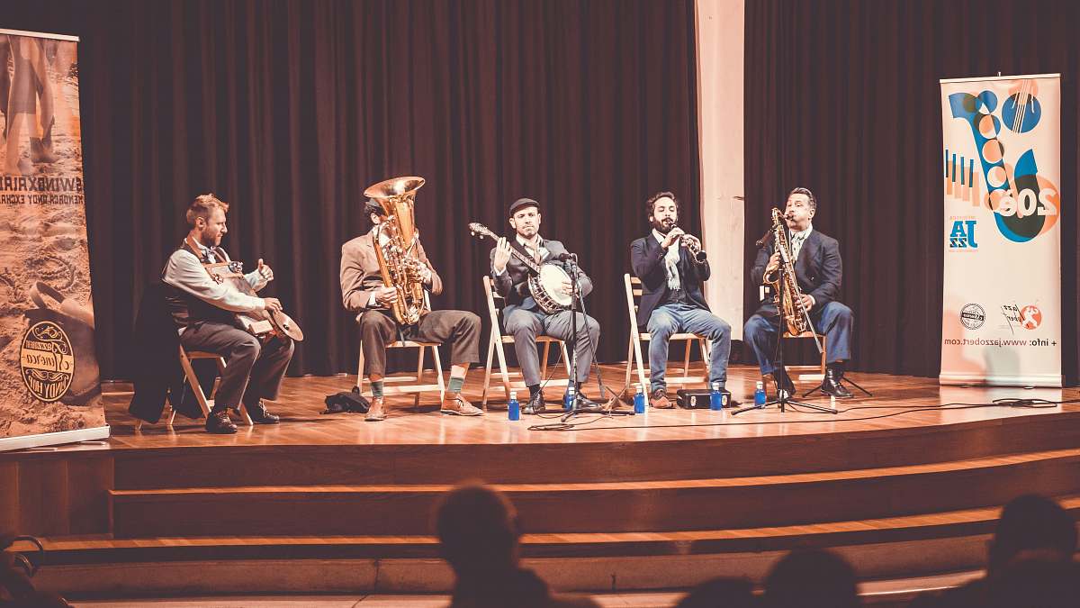 person five men playing instruments on stage people