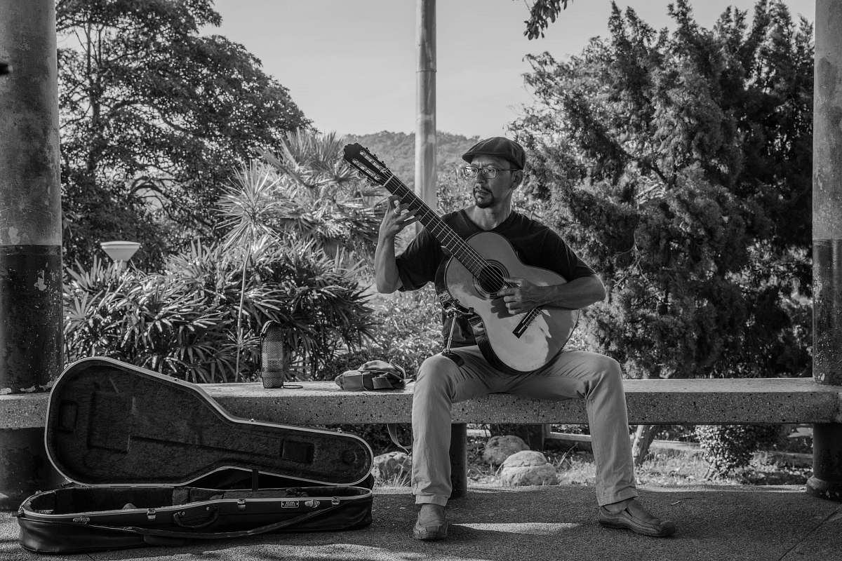 people grayscale photography of man playing classic guiar black-and-white