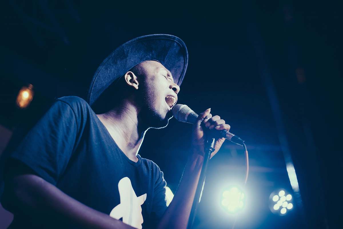 person low angle of man wearing cap singing in microphone people