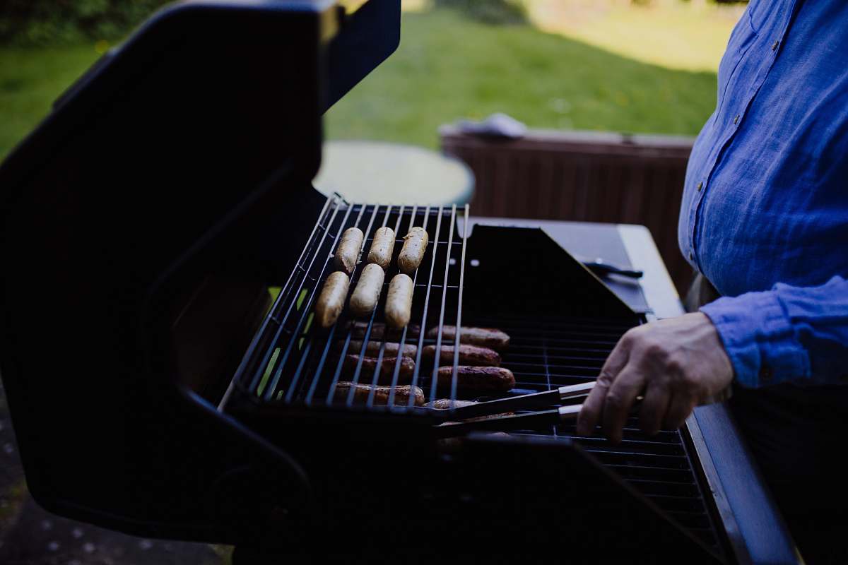 person man grilling sausage during daytime people