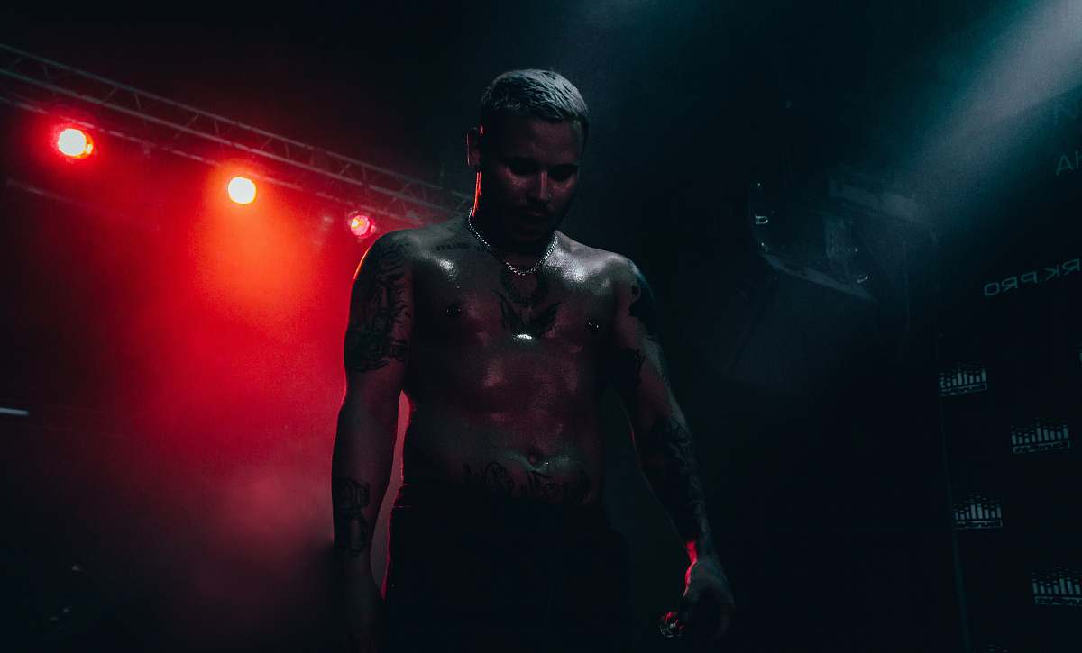 person man half naked standing on stage concert