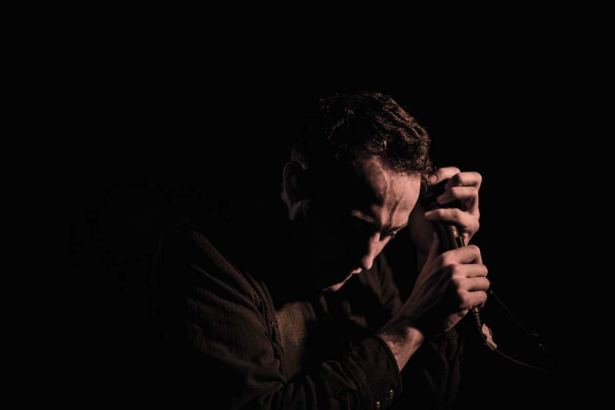 person man holding a black dynamic microphone on the dark people