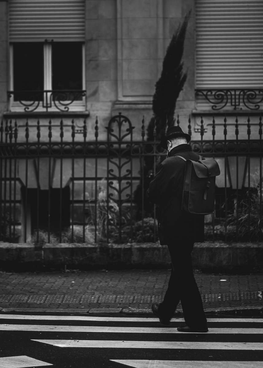 person man in black jacket walking on sidewalk black-and-white
