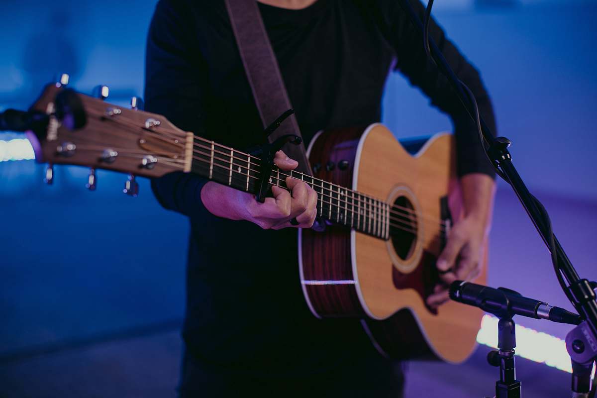 guitar man in black long sleeve shirt playing brown acoustic guitar musical instrument