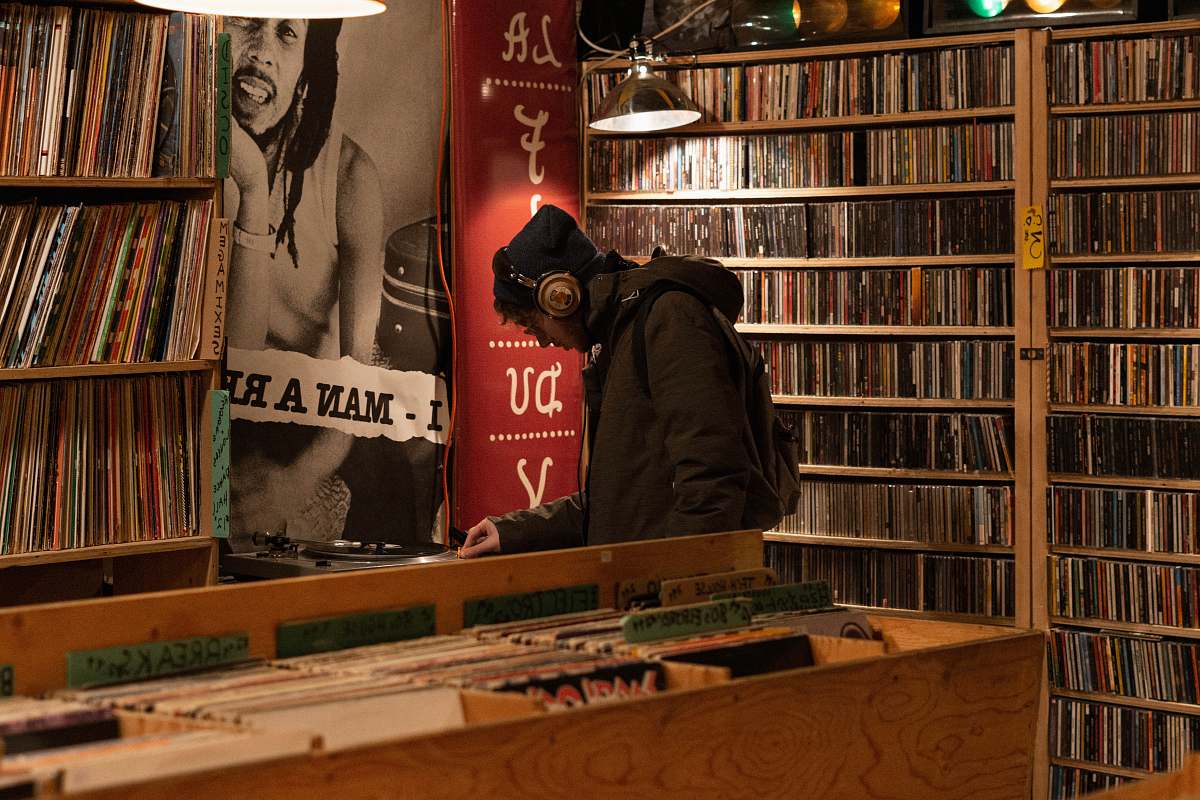 furniture man in hoodie and headphones standing inside record store shelf