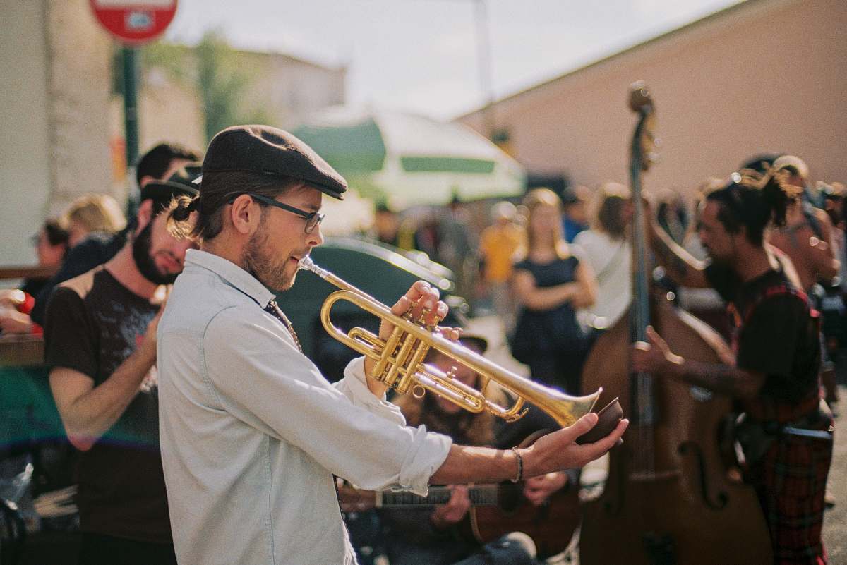 person man in white thobe playing trumpet during daytime trumpet