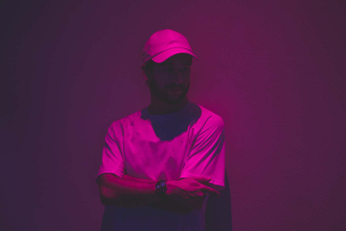 person man leaning of wall with purple light in fashion photography people