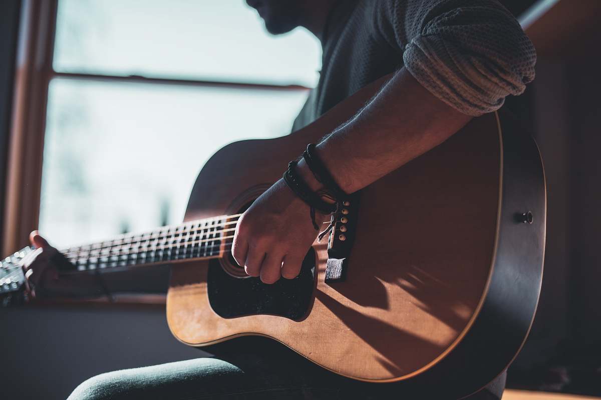 person man playing acoustic guitar selective focus photography people