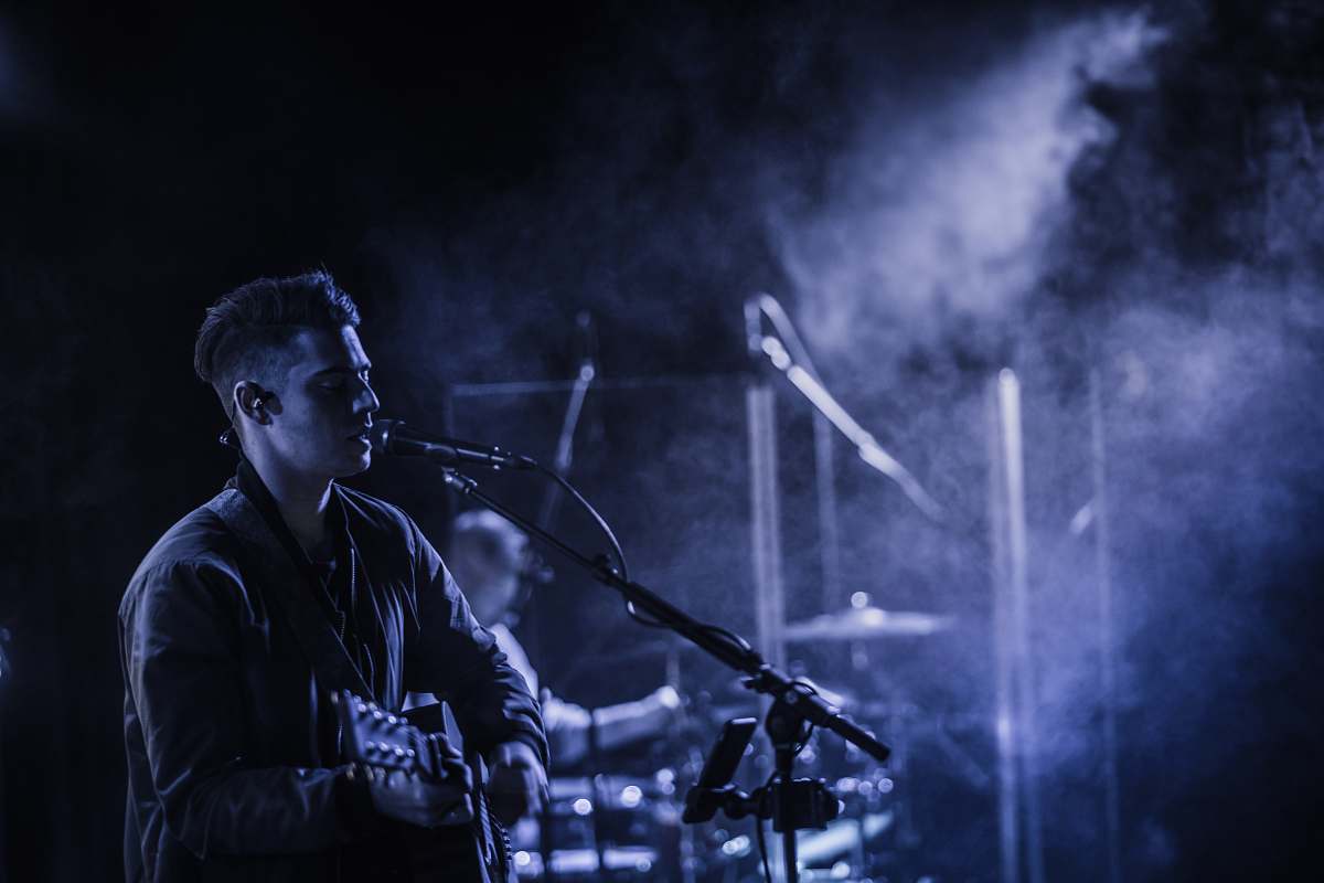 people man playing acoustic guitar while singing on stage person