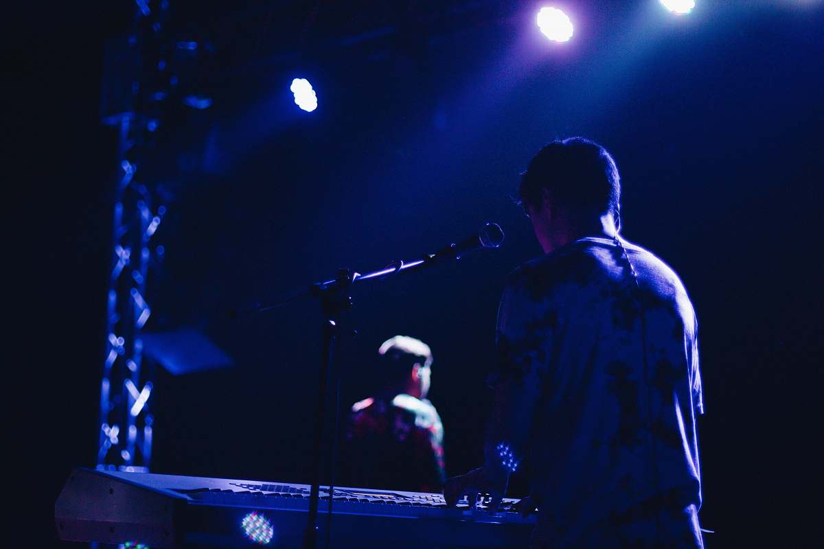 person man playing electric keyboard on stage lighting