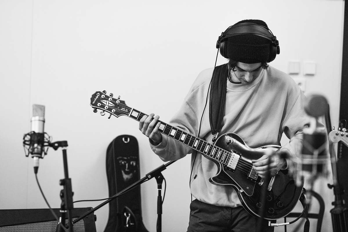 people man playing guitar inside a studio black-and-white