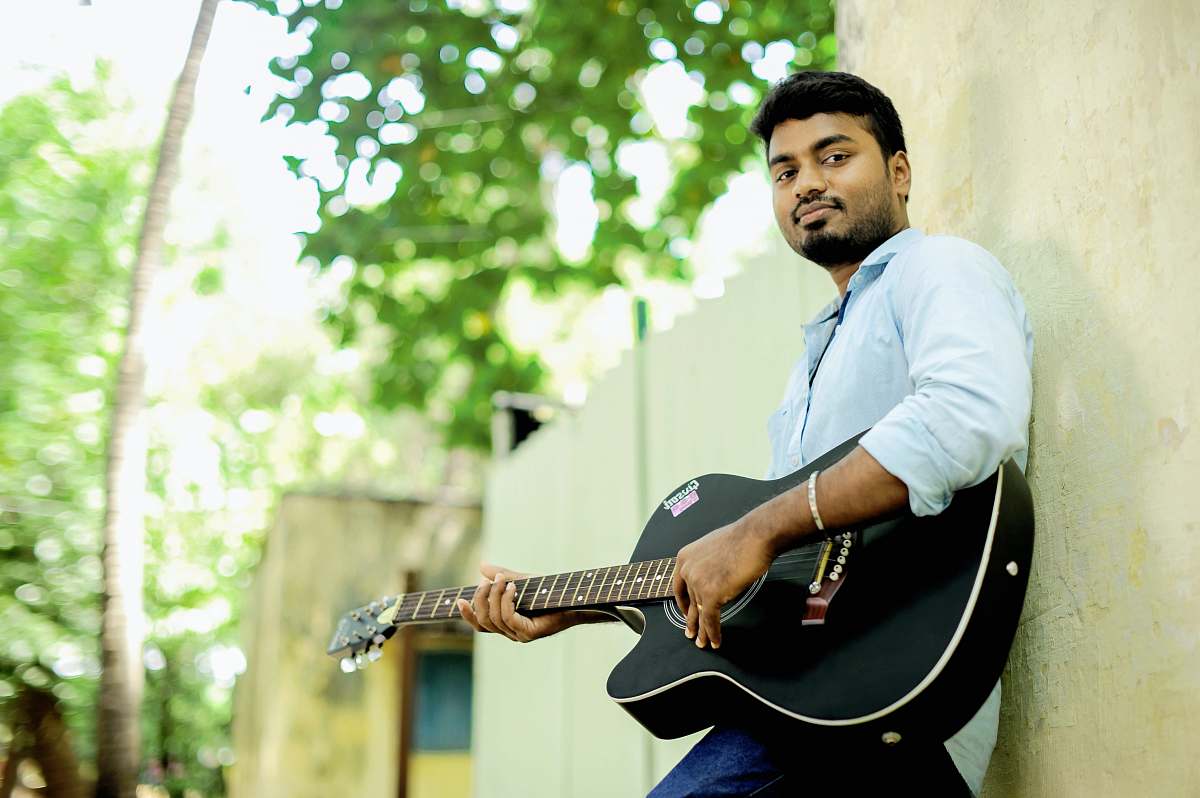 person man playing guitar leaning against wall people