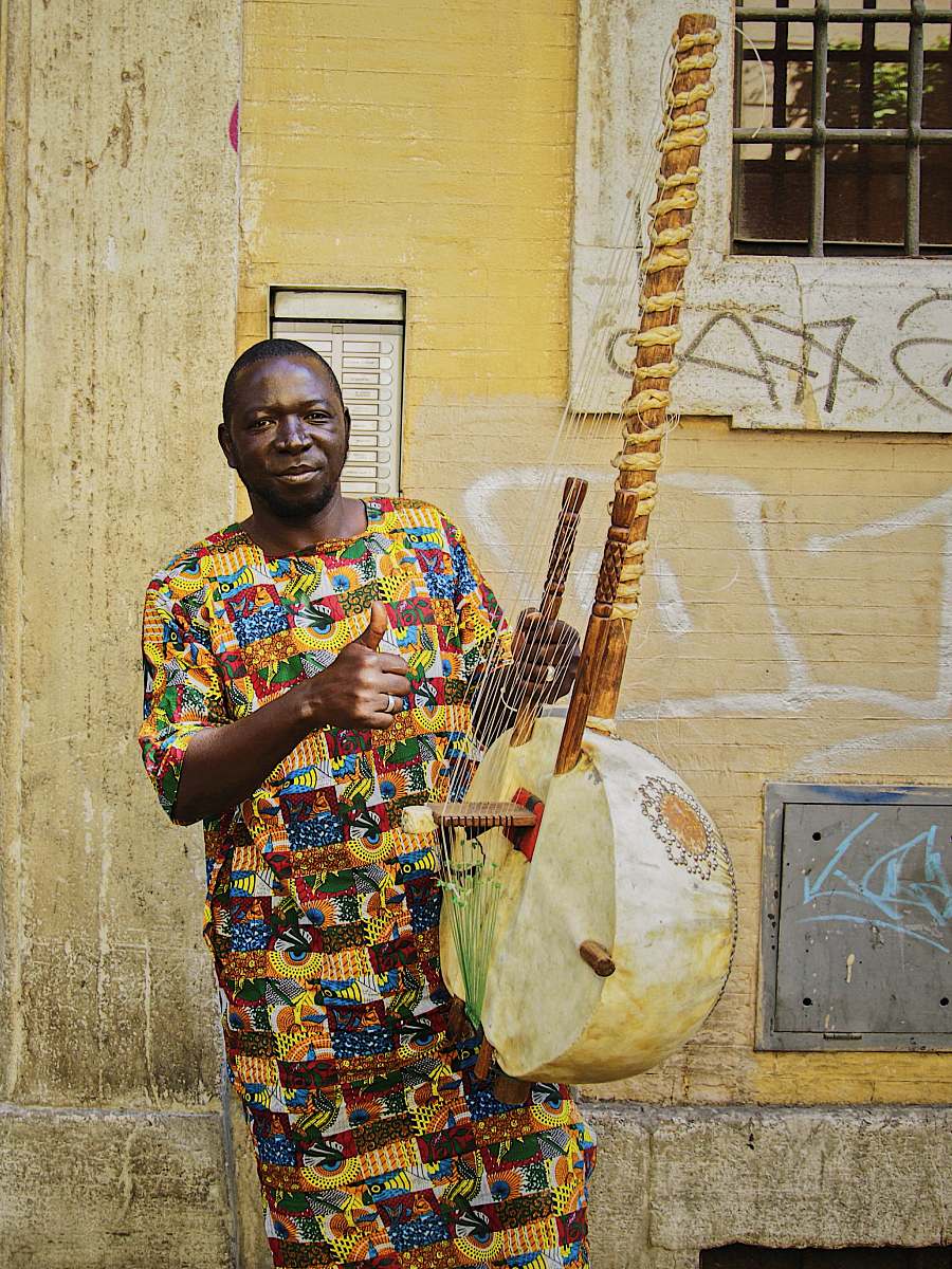 person man playing string instrument near wall people