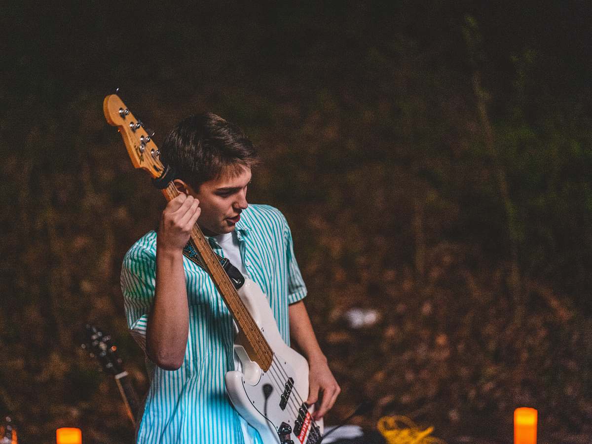 person man playing white electric guitar guitar