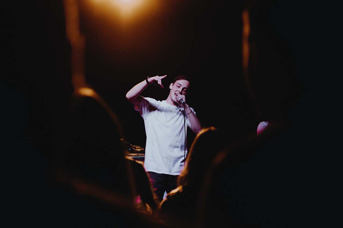 people man raising his left hand while singing person
