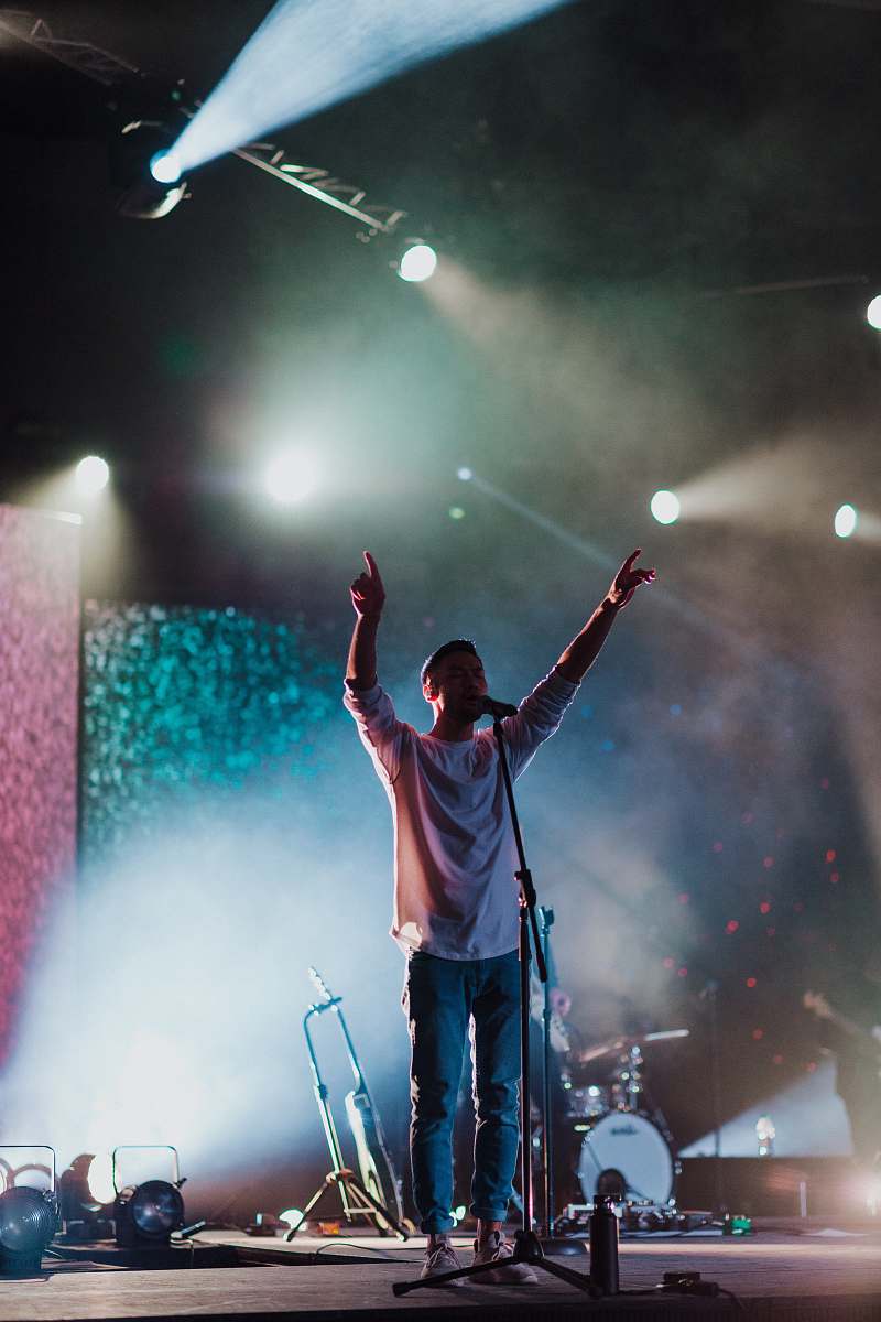 person man singing on stage at night-time crowd