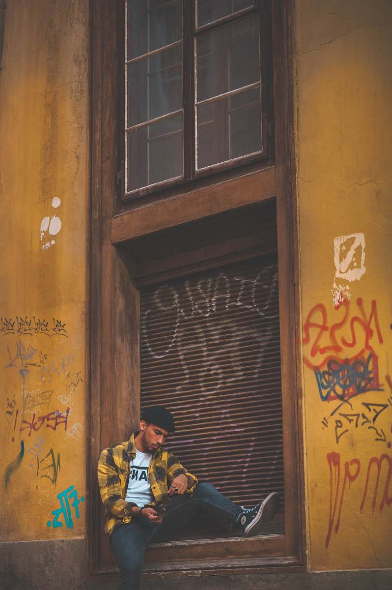 person man sitting beside shutter gate people