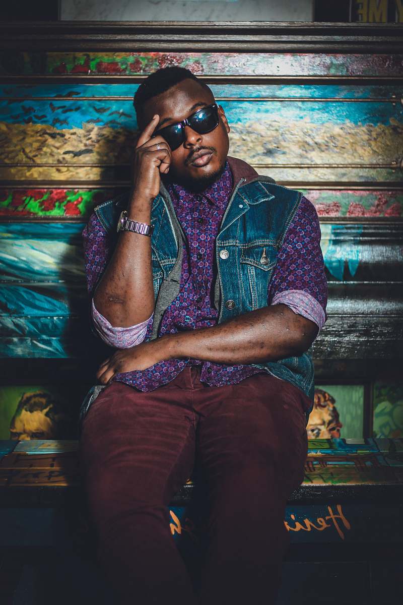 person man sitting wearing sunglasses leaning on floral bench people