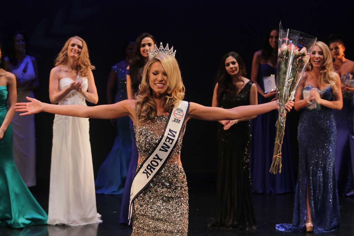 person Miss New York spreading her arms while smiling people