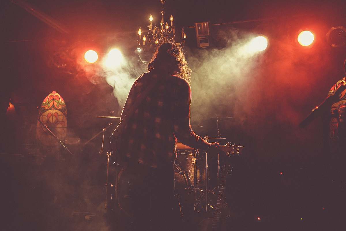 person person standing on stage holding guitar close-up photography crowd