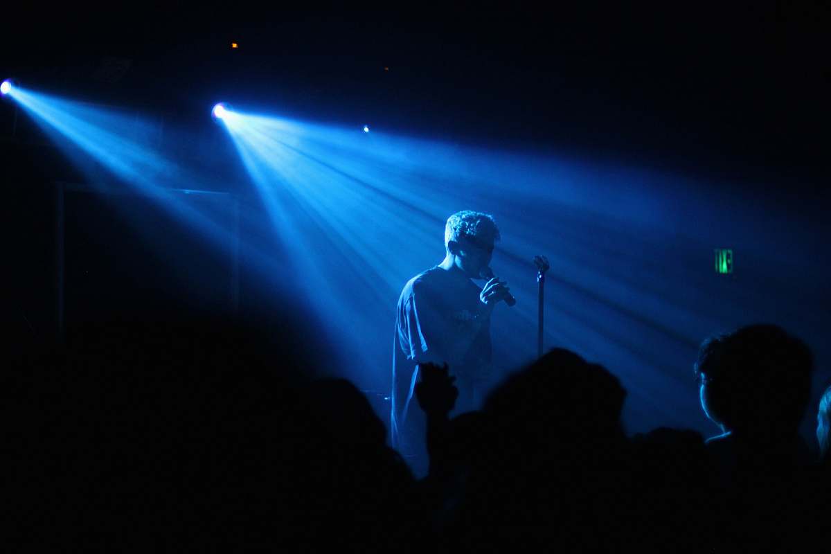 person photo of man performing on stage lighting