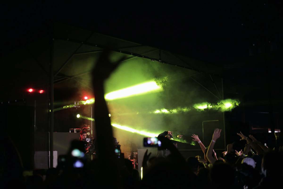 person silhouette of crowd raising hands fronting concert stage people