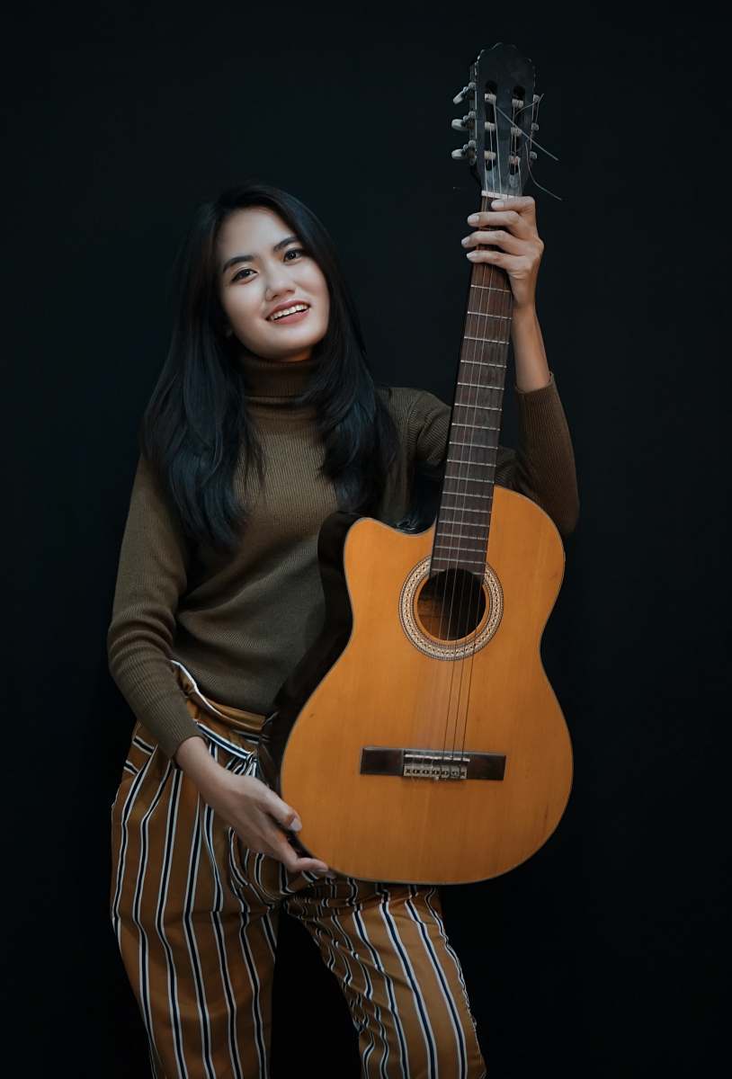 person smiling woman while holding cut-away acoustic guitar people