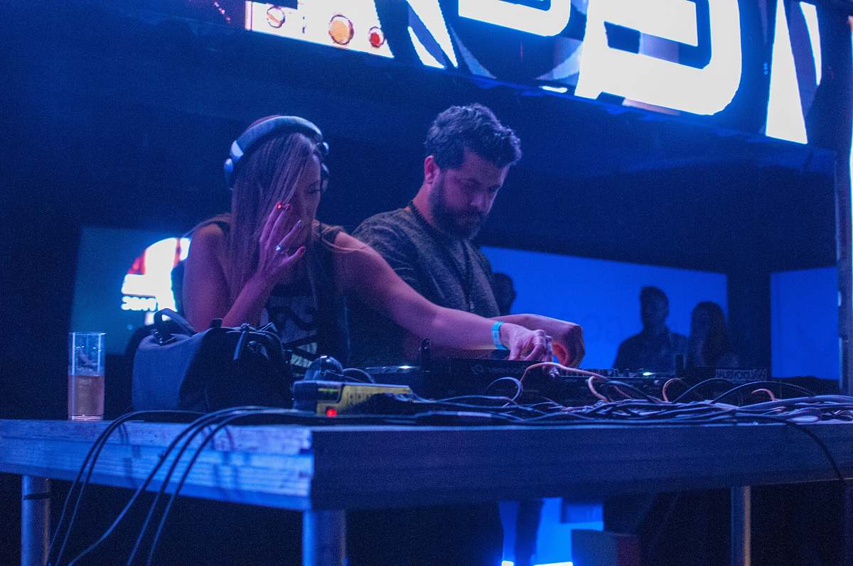people woman playing DJ controller beside man in gray shirt person