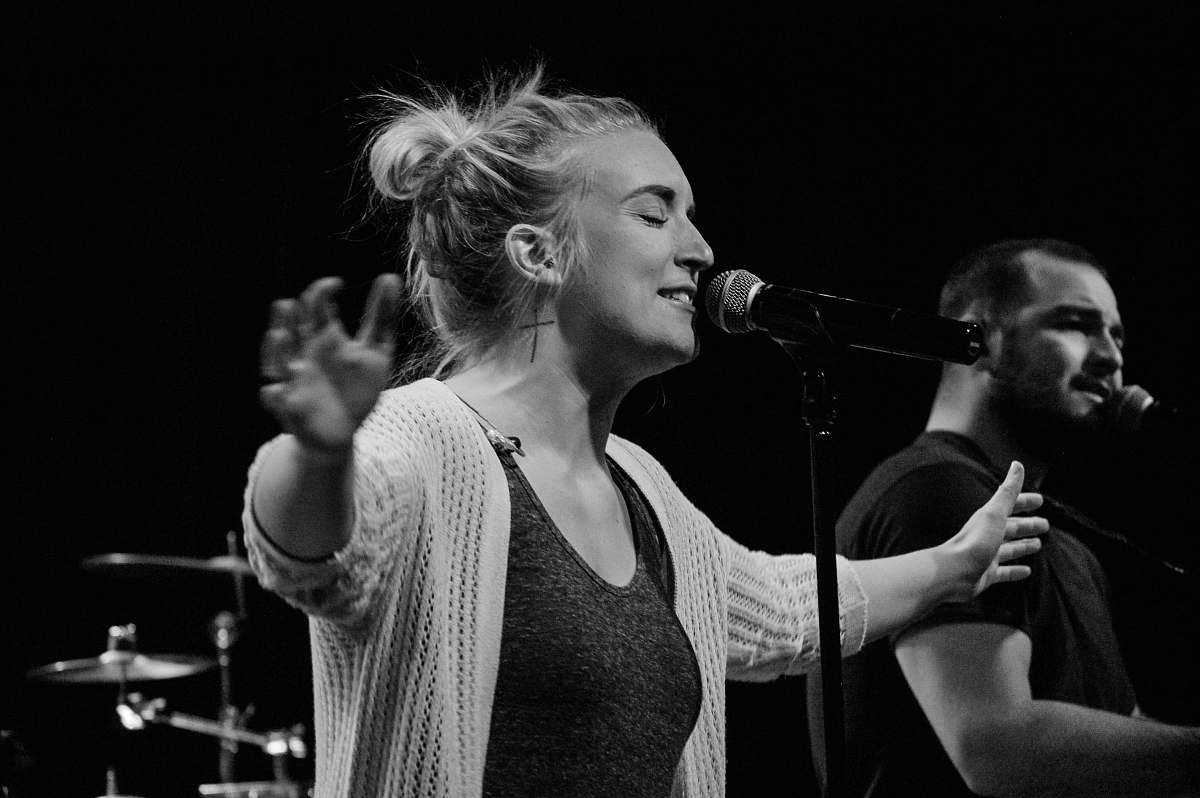 person woman standing front of microphone black-and-white