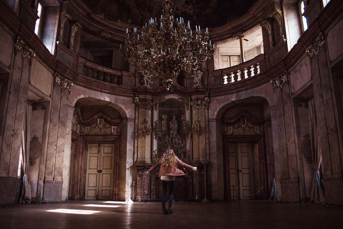 person woman standing under gold chandelier indoors chandelier