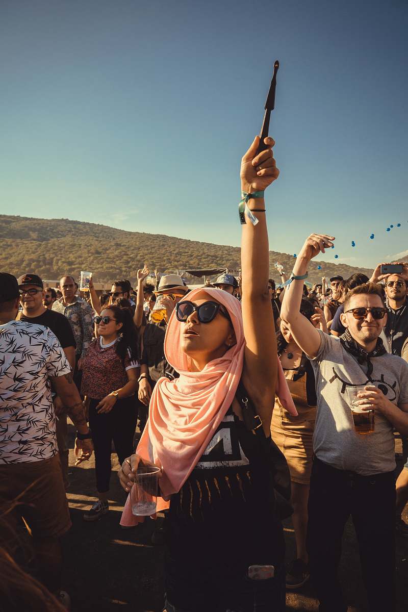 person woman with pink shawl raising her right hand in front of people accessories