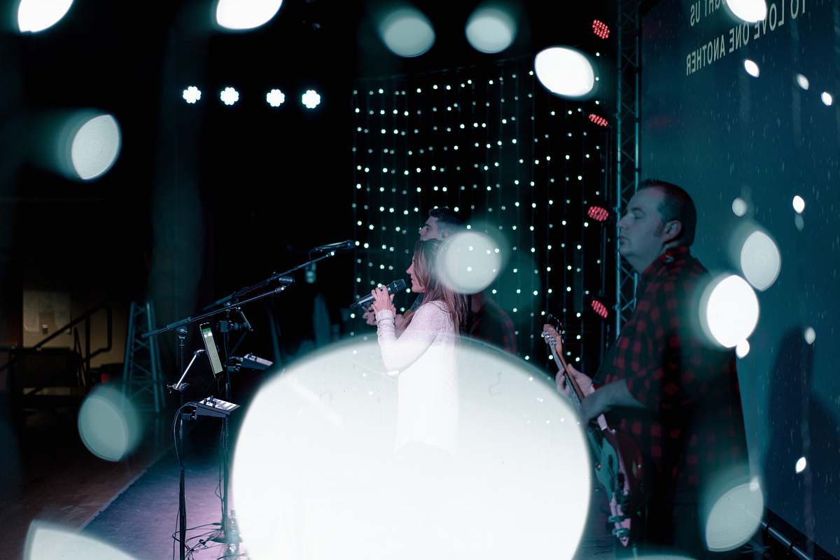 stage woman singing and man playing guitar on stage drum