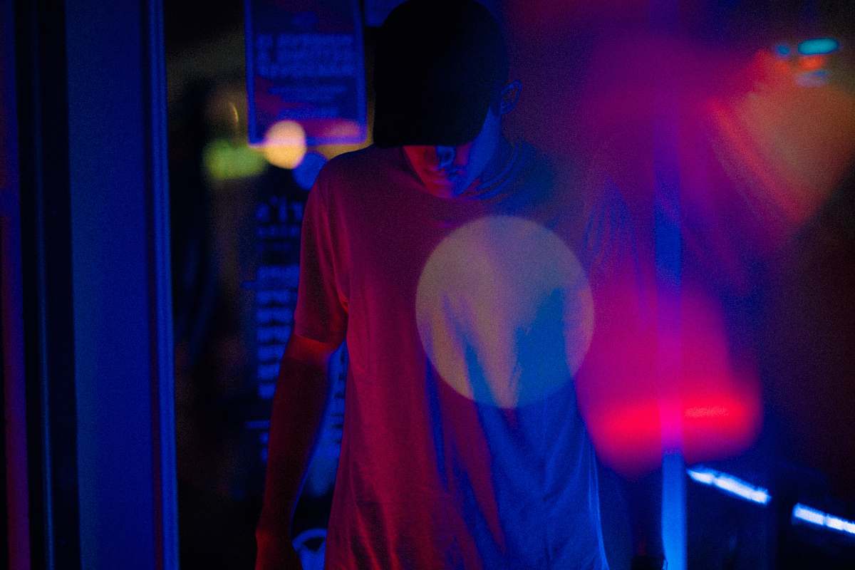 male man wearing crew-neck shirt and black trucker hat night