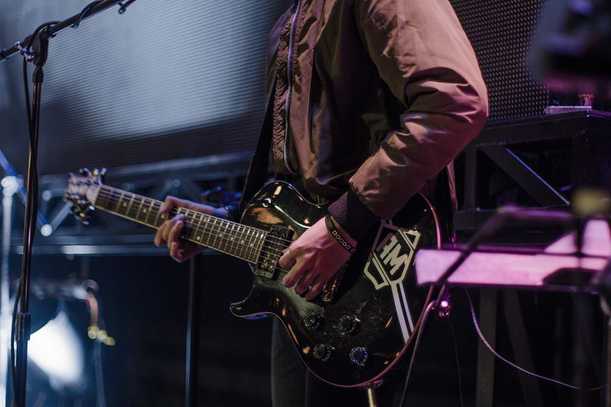 guitar man playing black electric guitar beside black microphone with stand person