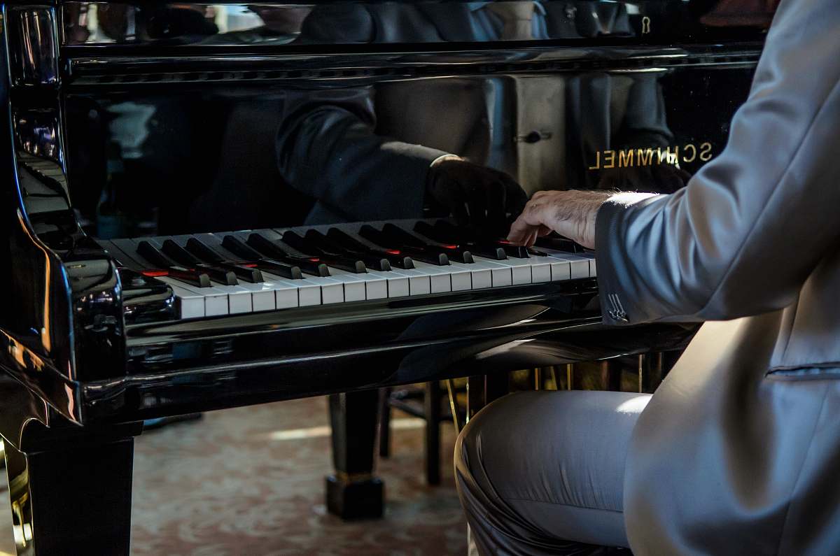 piano man sits on bench playing piano grand piano