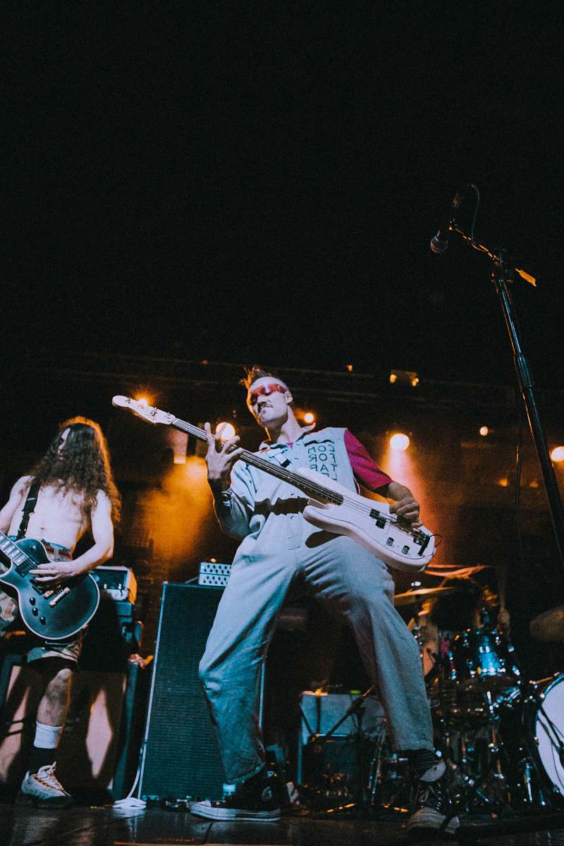 person man standing on stage playing electric bass guitar guitar