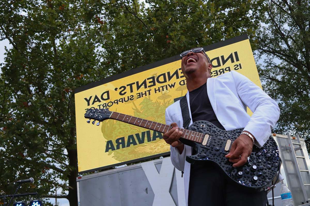 guitar man standing on stage while playing black electric guitar person
