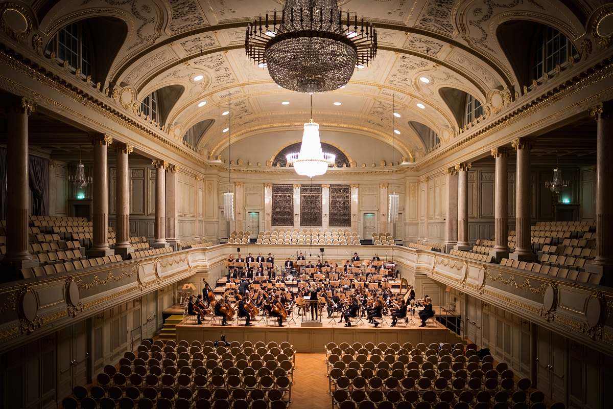 ballroom music group performing on stage with empty audience seats indoors