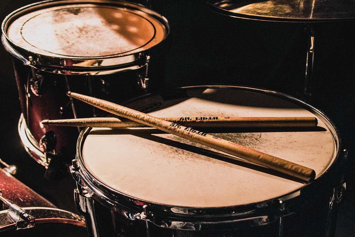 drum pair of brown wooden drumsticks on top of white and gray musical drum leisure activities