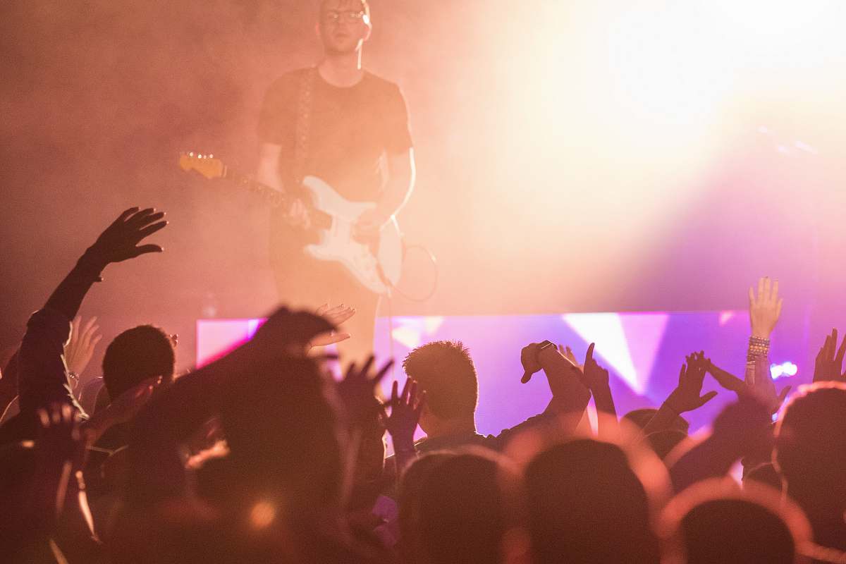 person people watching man playing guitar on stage crowd