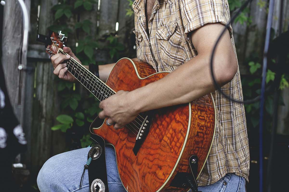human person holding brown guitar outdoor person
