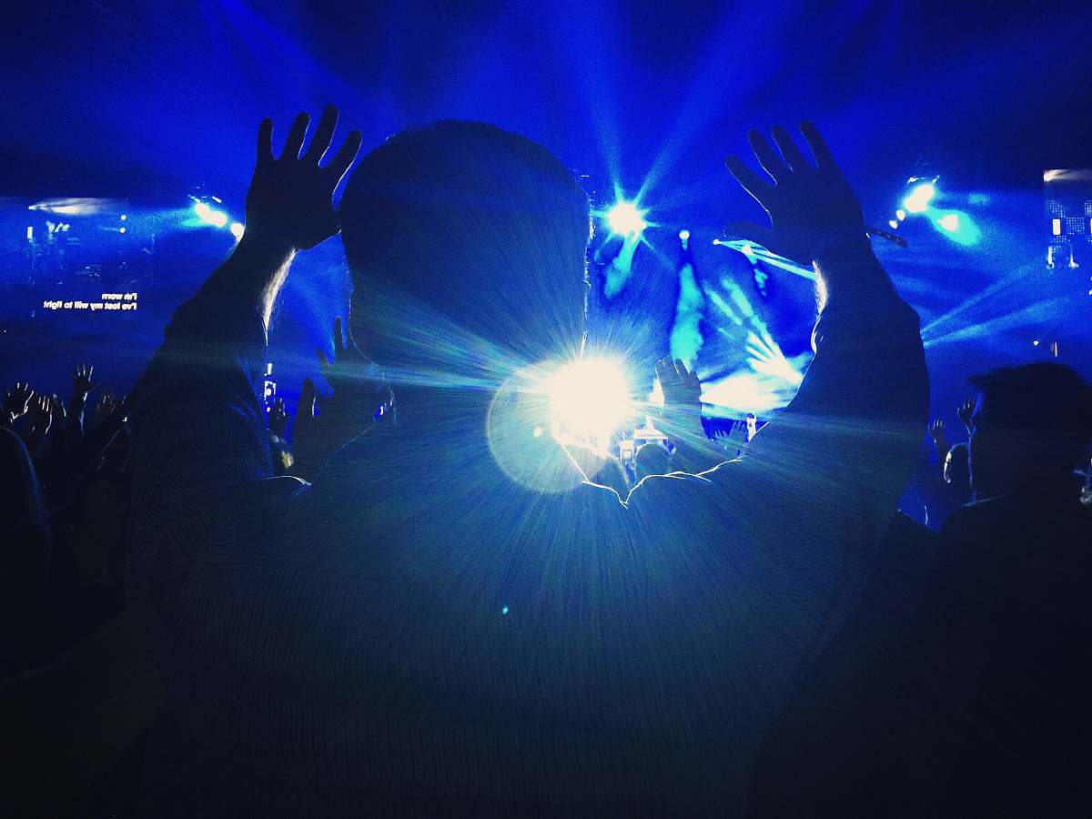 church silhouette of a person raising hands towards the stage portland