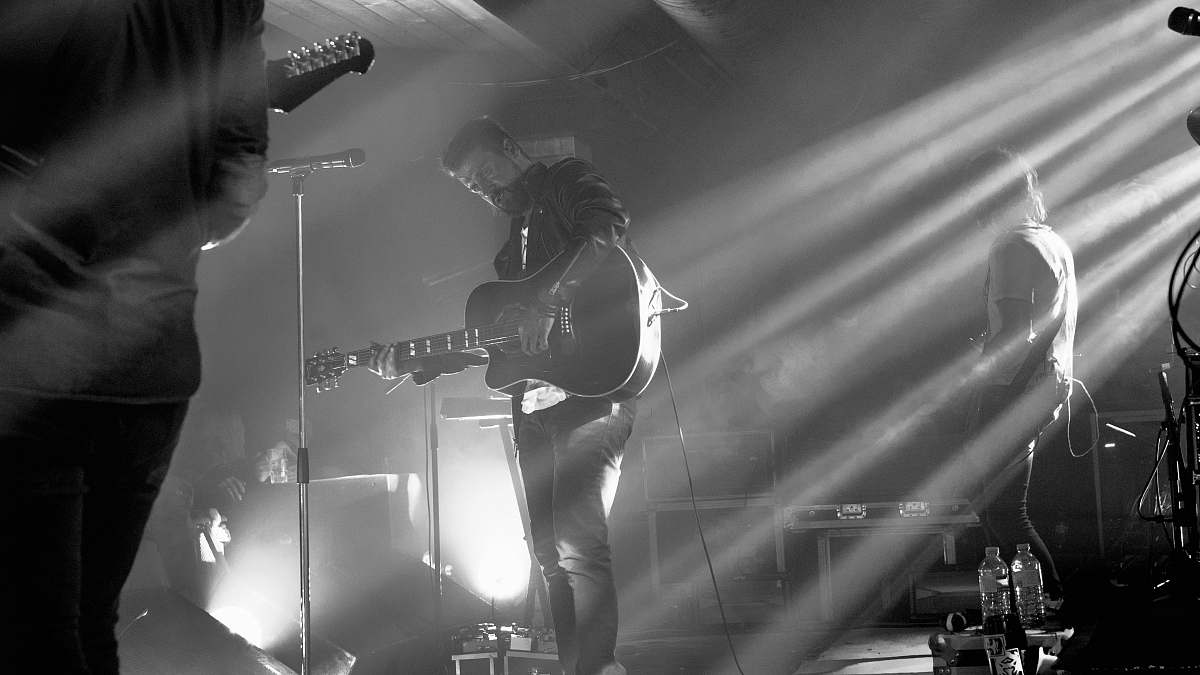 guitar grayscale photography of band member performing on stage black-and-white