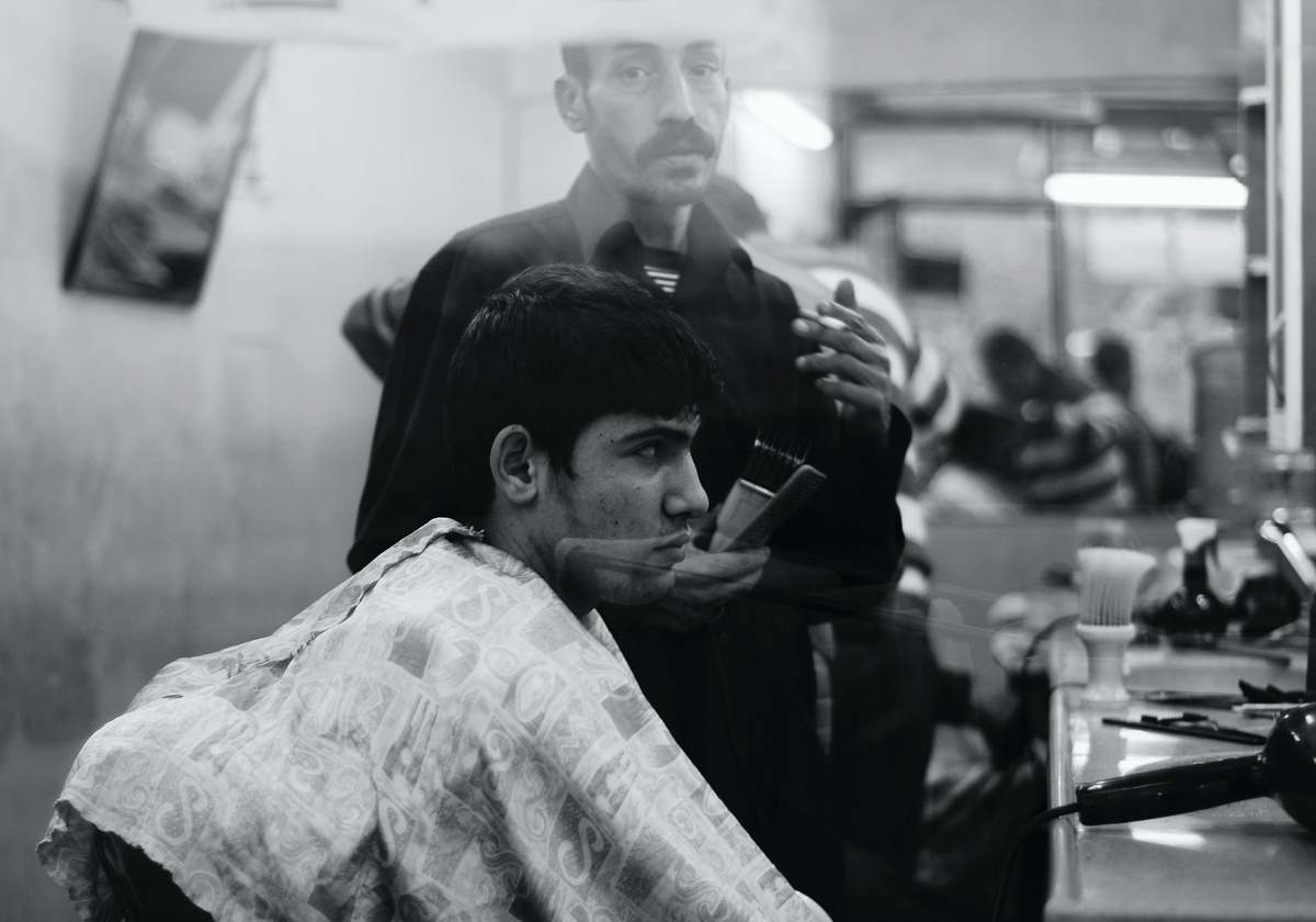 person grayscale photo of man inside barber shop black-and-white