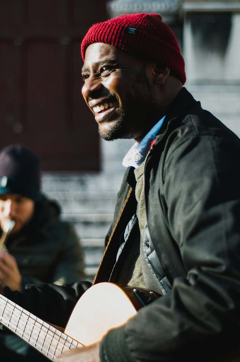 person man holding guitar near man playing flute human