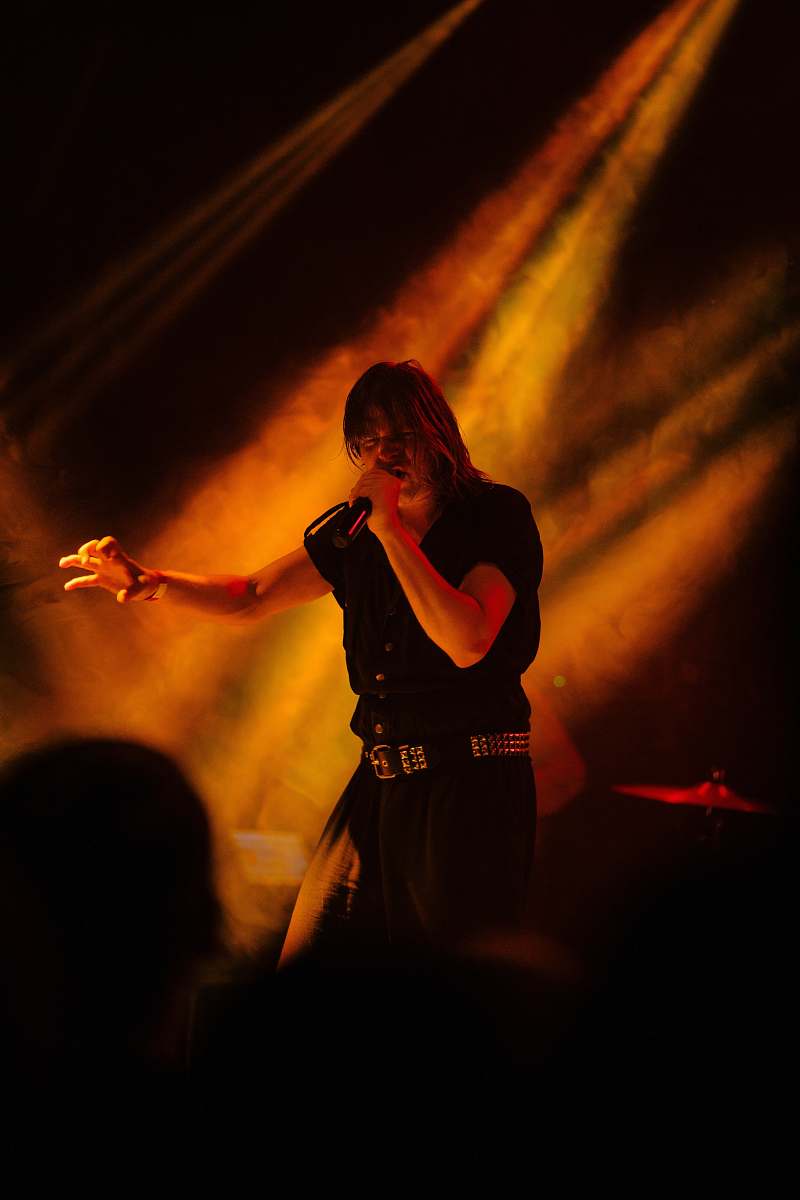 human man holding microphone standing on stage with lightings person