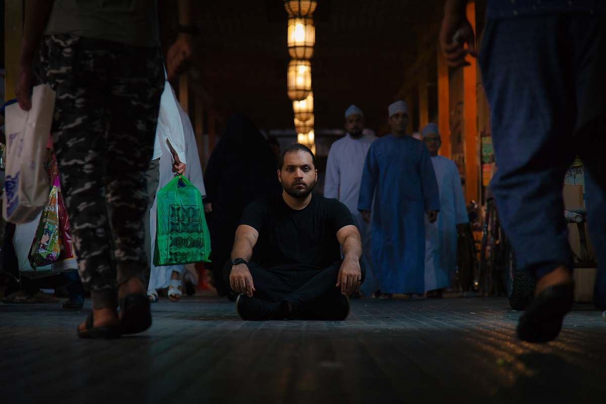 person man in black shirt sitting on floor surrounded by people human
