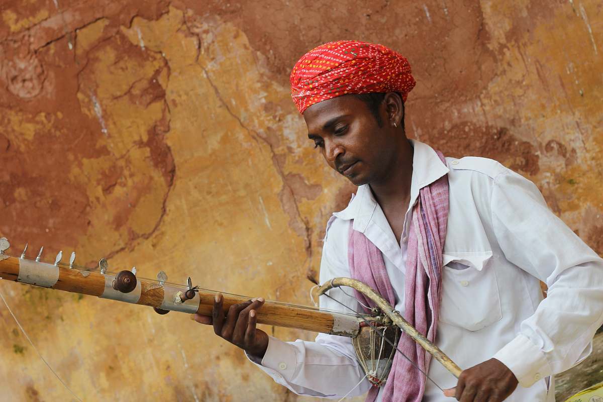 human man in red turban playing musical instrument person