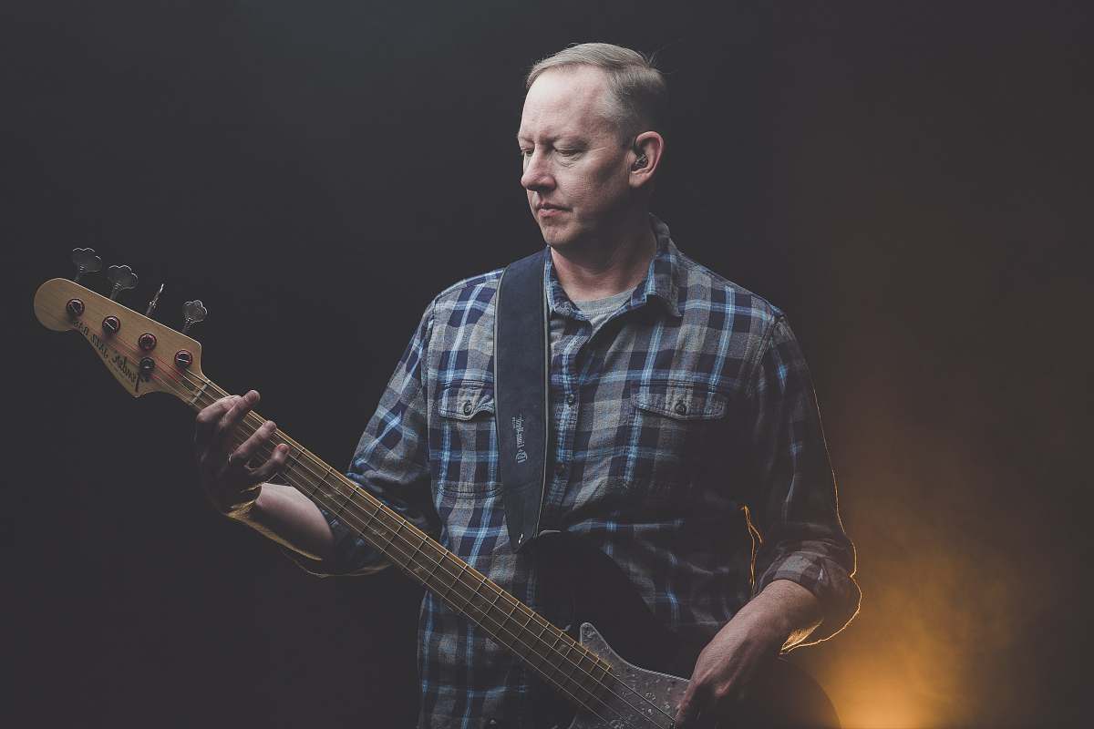 human man playing electric guitar in dark room person
