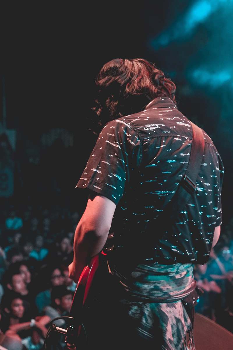 person man playing red electric guitar during concert human